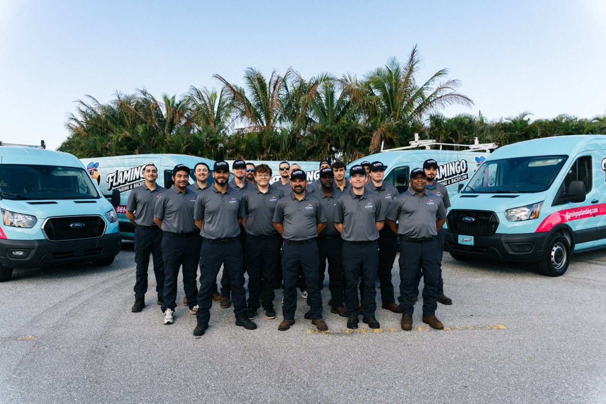The Flamingo Plumbing technician team in front of the branded fleet