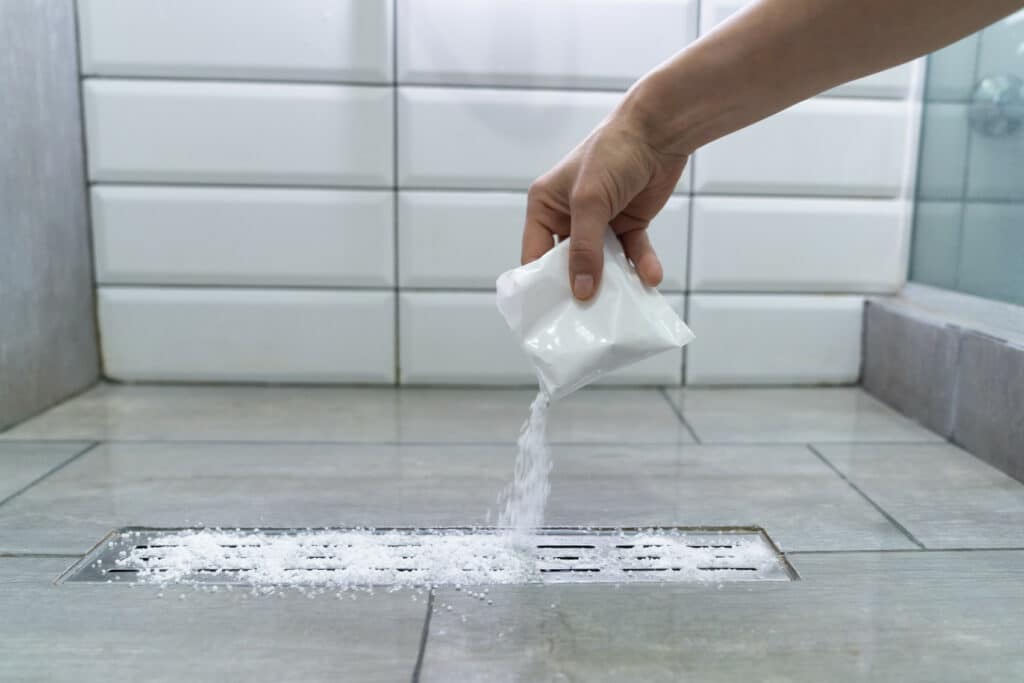 woman cleaning a shower drain